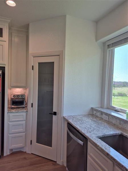 Kitchen featuring light stone counters, stainless steel dishwasher, dark wood-type flooring, recessed lighting, and white cabinetry