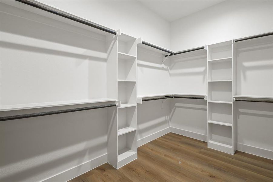 Walk in closet with hardwood / wood-style flooring