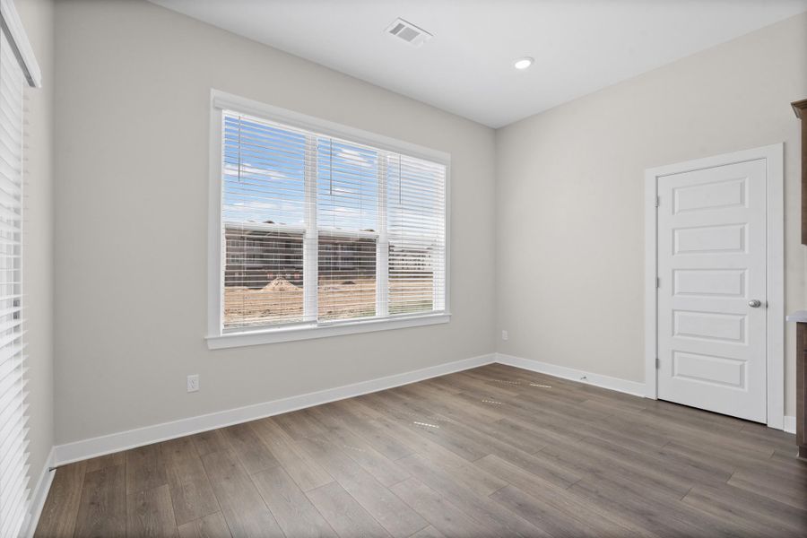 Expansive window with horizontal blinds, wood-finish flooring, recessed ceiling lighting, and a five-panel interior door