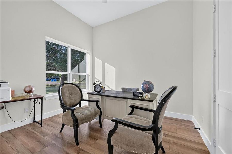 Spacious room featuring wood-finish flooring, a large window, a built-in desk, and vaulted ceilings Spacious room featuring wood-finish flooring, a large window, a built-in desk, and vaulted ceilings