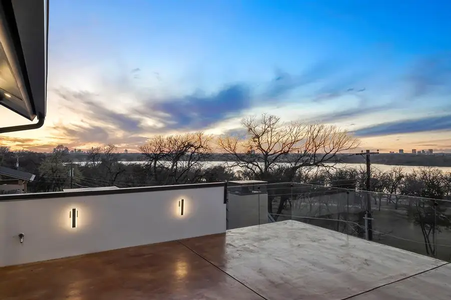 Rooftop deck featuring a glass railing system, concrete flooring, and modern wall sconces