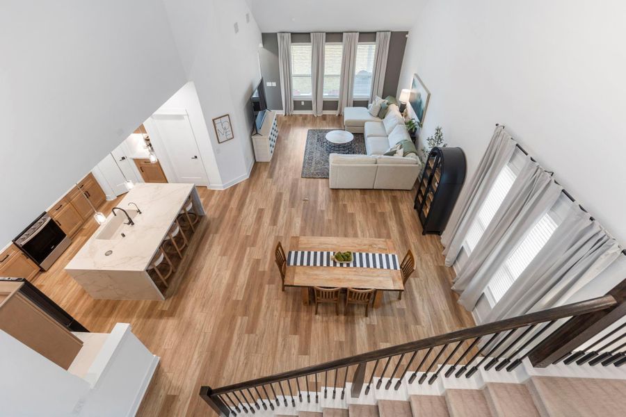 This bright, open-concept living area features high ceilings and large windows, highlighting a spacious living room with a sectional sofa. The modern kitchen includes a marble island with bar seating and sleek appliances. Adjacent is a cozy dining area, all set on elegant wood flooring. This bright, open-concept living area features high ceilings and large windows, highlighting a spacious living room with a sectional sofa. The modern kitchen includes a marble island with bar seating and sleek appliances. Adjacent is a cozy dining area, all set on elegant wood flooring.