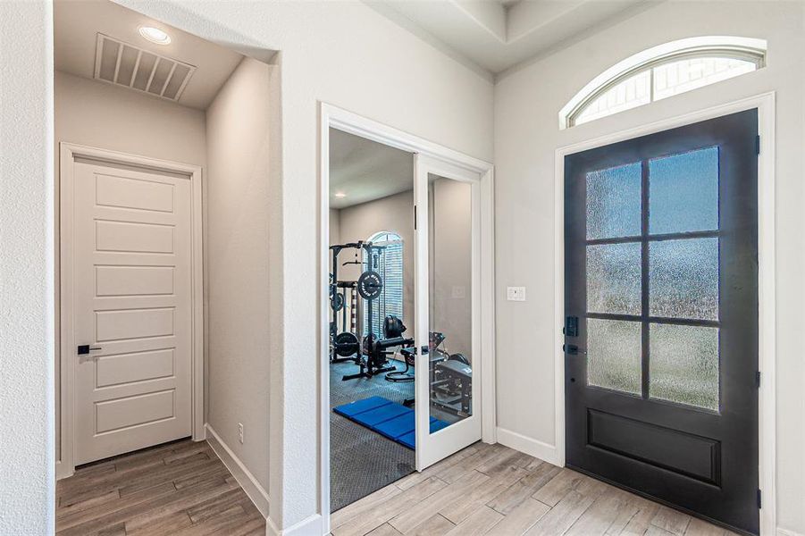 Entryway featuring wood-finish tile flooring, a black front door with frosted glass panels, and an arched transom window