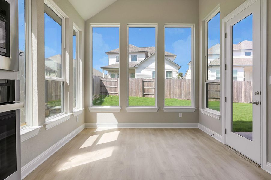 Unfurnished sunroom with wood finished floors, plenty of natural light, and vaulted ceiling