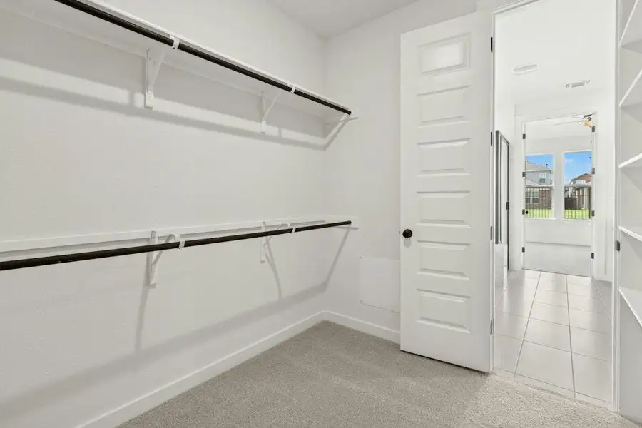 Spacious closet with light colored carpet and light tile patterned flooring
