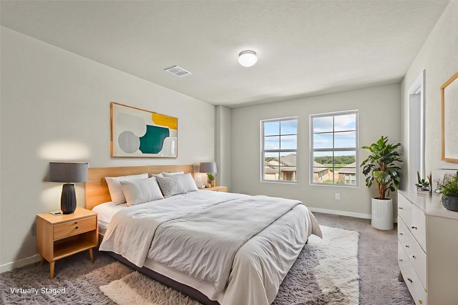 A tranquil primary bedroom offers comfort with soft carpeting and ample natural illumination through multiple windows.