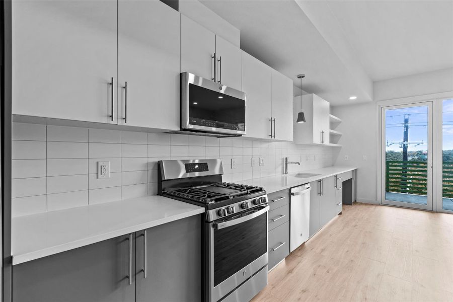 Kitchen featuring stainless steel appliances, light wood-type flooring, light countertops, and a sink