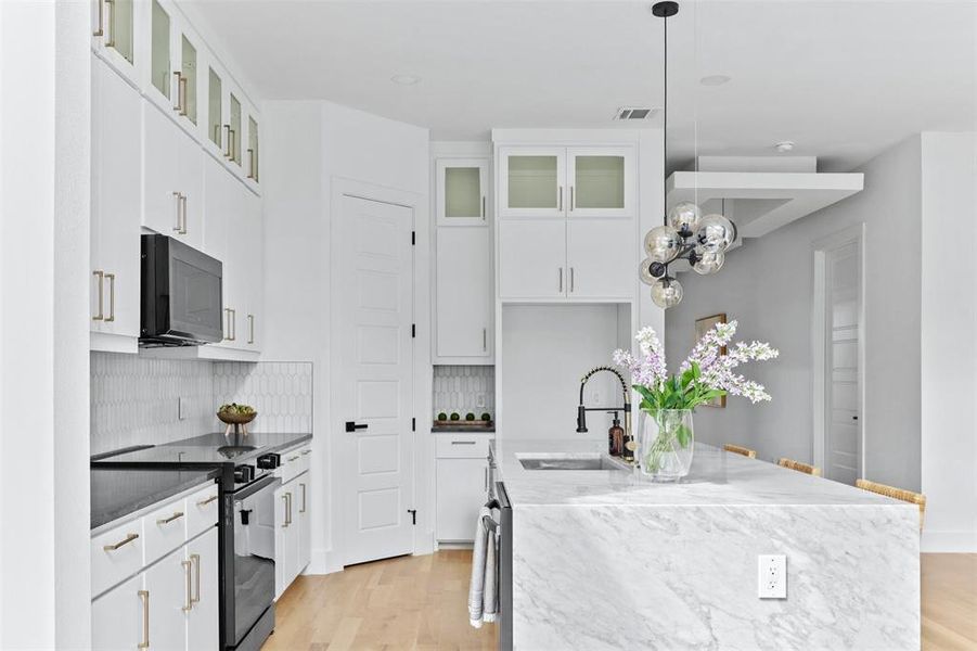 Kitchen with electric stove, light hardwood / wood-style floors, white cabinetry, and sink