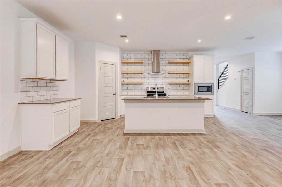 A true chef’s delight, this kitchen blends form and function with quartz surfaces, sleek stainless vent hood, gas range, built-in microwave, and open wood shelving for a custom touch. Crisp white cabinetry and classic subway tile elevate the entire space with modern elegance. A true chef’s delight, this kitchen blends form and function with quartz surfaces, sleek stainless vent hood, gas range, built-in microwave, and open wood shelving for a custom touch. Crisp white cabinetry and classic subway tile elevate the entire space with modern elegance.
