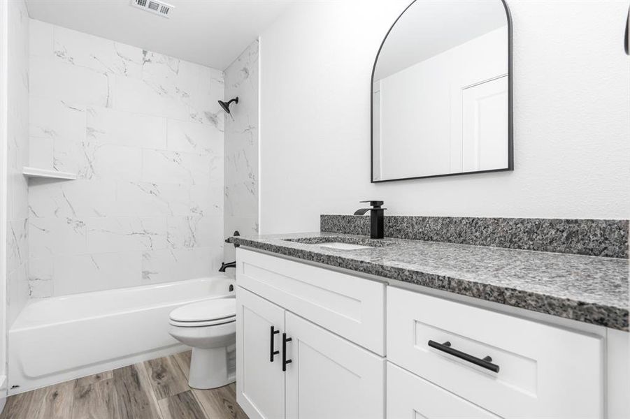 Full bathroom featuring  shower combination, vanity, and light wood finished floors