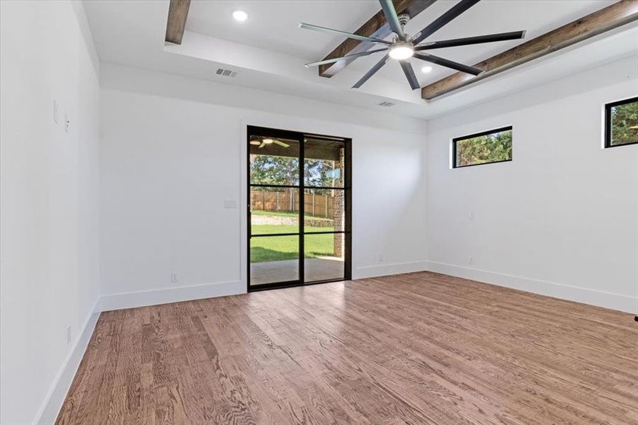 Spare room with wood-type flooring, ceiling fan, and a tray ceiling