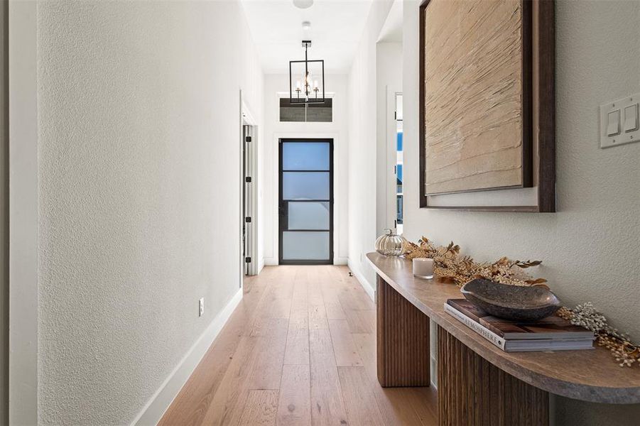 Doorway featuring a textured wall, hardwood / wood-style flooring, and a chandelier Doorway featuring a textured wall, hardwood / wood-style flooring, and a chandelier