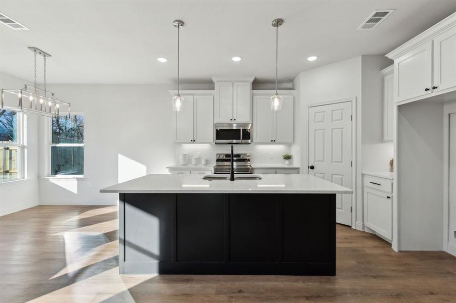 Kitchen with a kitchen island with sink, white cabinetry, sink, and stainless steel appliances