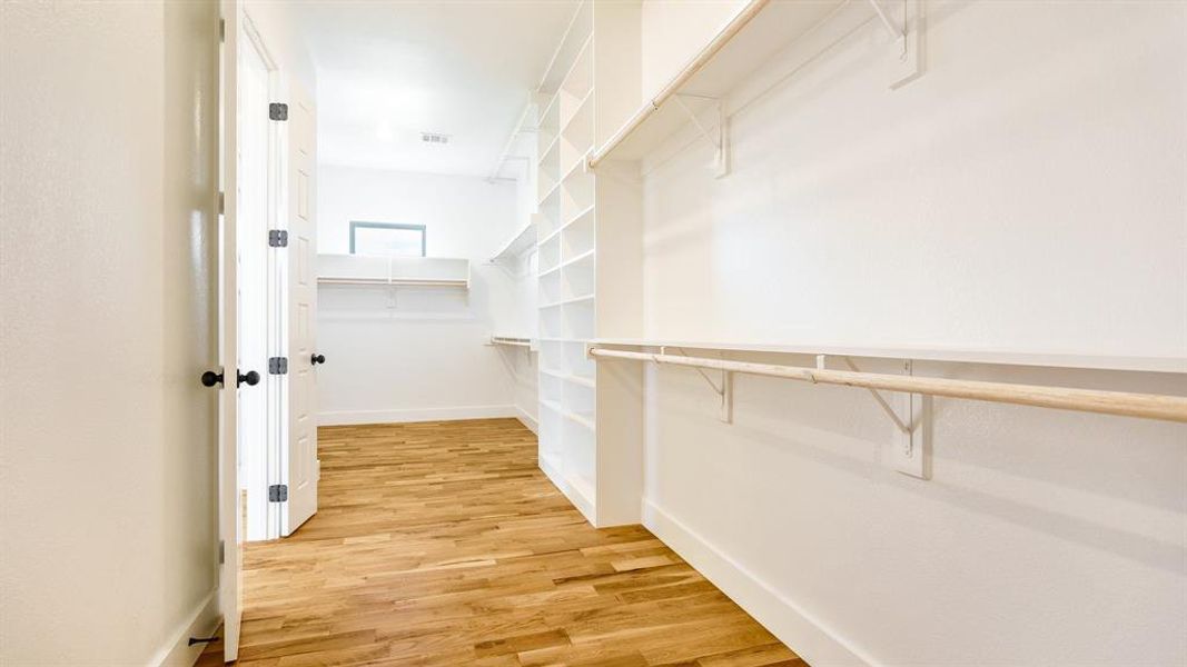 Walk in closet with light wood-type flooring