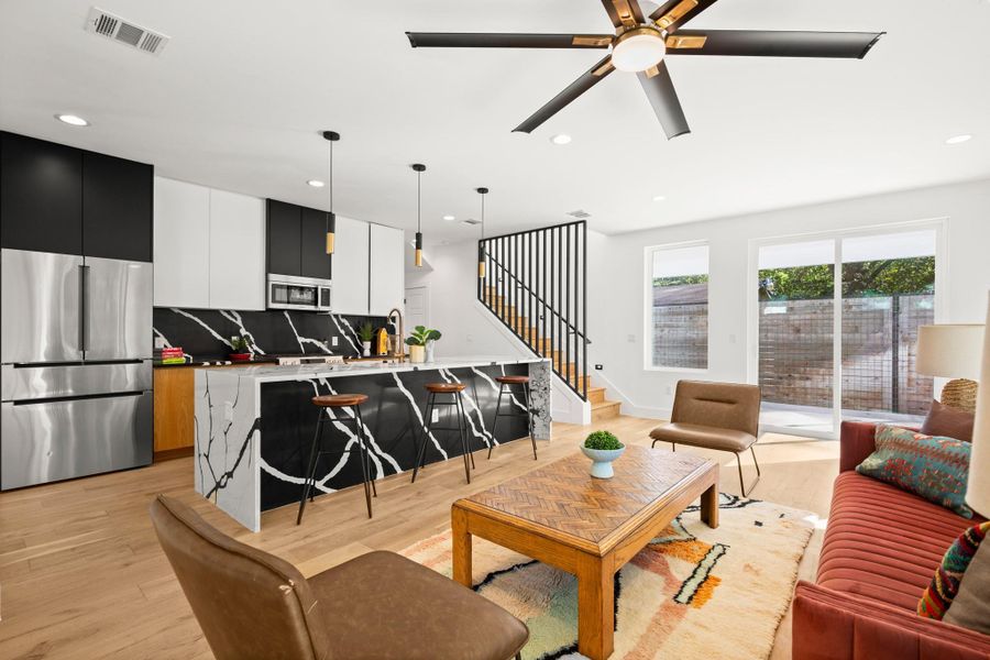 Living area with light wood-type flooring, recessed lighting, ceiling fan, and stairway Living area with light wood-type flooring, recessed lighting, ceiling fan, and stairway