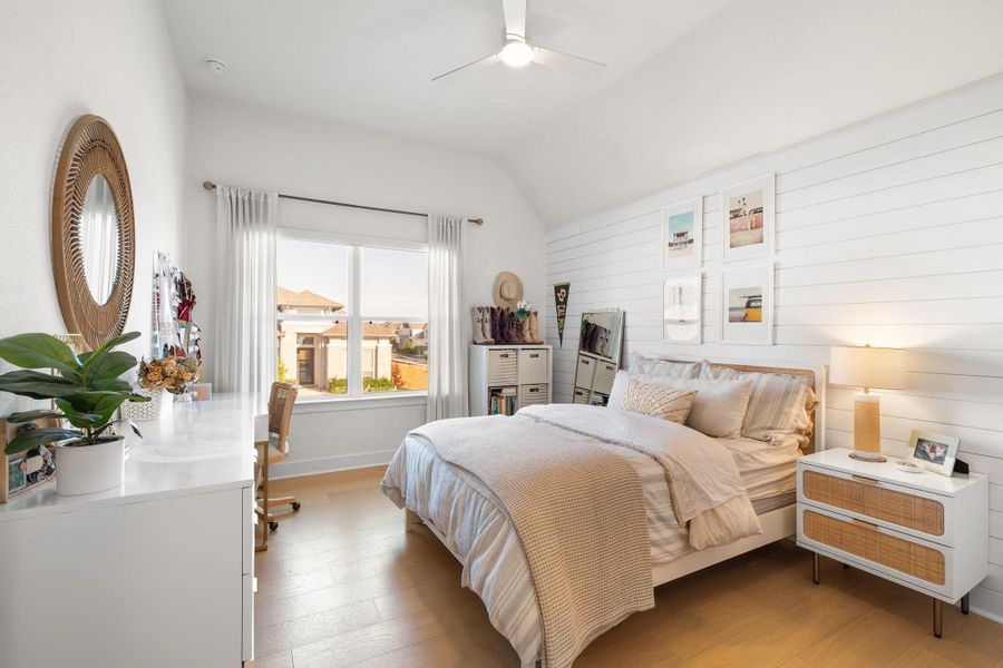 Bedroom featuring vaulted ceilings, wood-finish flooring, a contemporary ceiling fan, and a shiplap accent wall Bedroom featuring vaulted ceilings, wood-finish flooring, a contemporary ceiling fan, and a shiplap accent wall