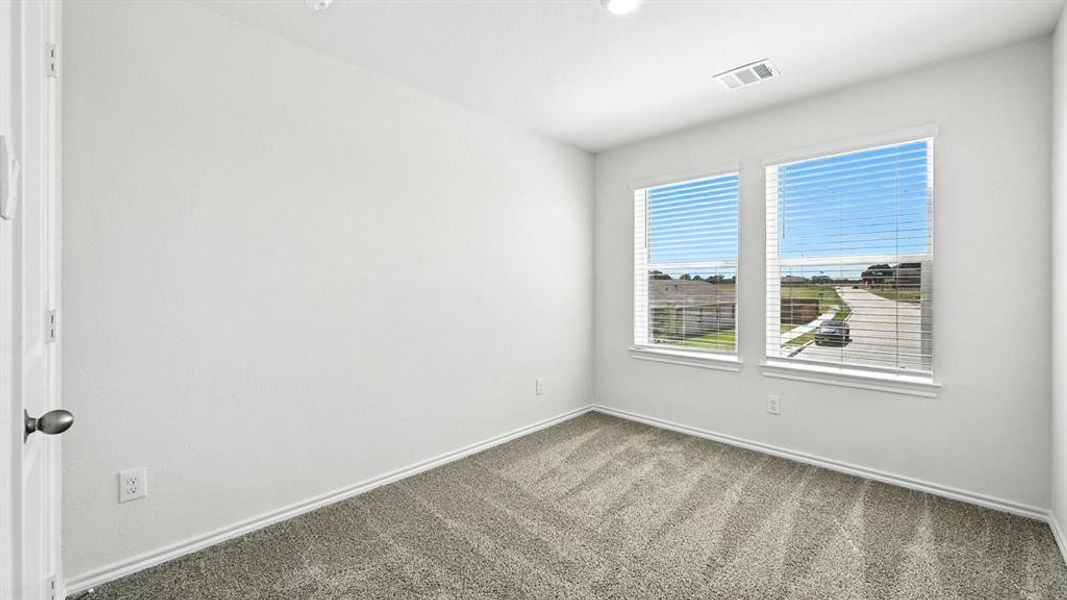 Bright interior room featuring two large windows with blinds, light gray textured carpet, white baseboards, and a neutral wall color