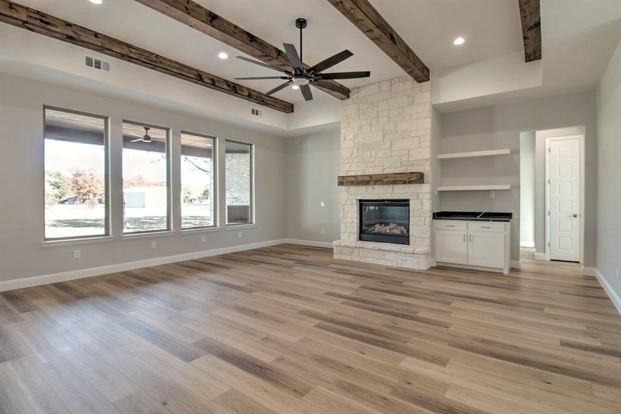 Unfurnished living room featuring beamed ceiling, light hardwood / wood-style floors, and a fireplace