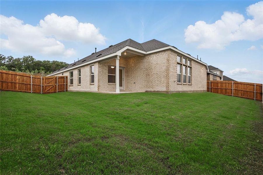 Rear view of house featuring a fenced backyard, brick siding, and roof with shingles Rear view of house featuring a fenced backyard, brick siding, and roof with shingles