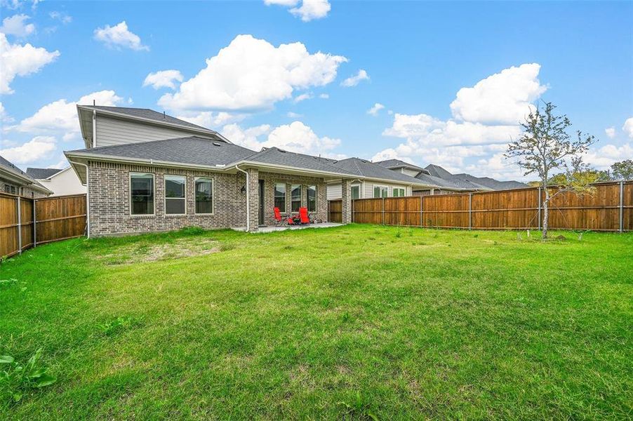 Rear view of house with a covered patio, brick siding, a fenced backyard, and a shingled roof