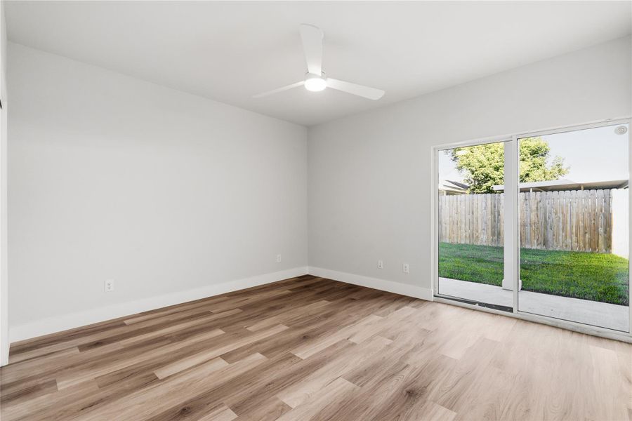 An additional view of the oversized secondary bedroom highlights the ceiling fan and expansive sliding glass doors that open directly to the private yard creating a rare indoor–outdoor connection typically reserved for primary suites.