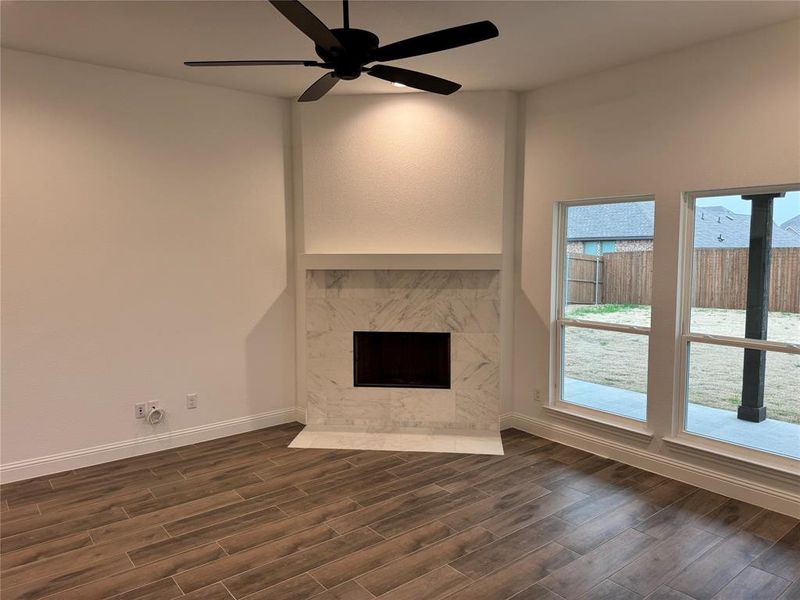 Unfurnished living room featuring dark hardwood / wood-style flooring, a fireplace, and ceiling fan