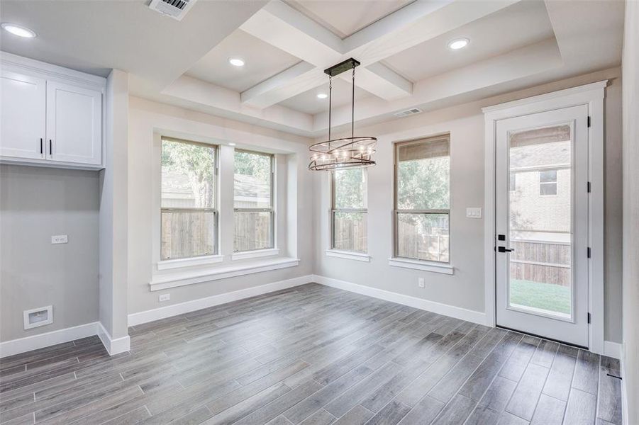 Dining area with coffered ceiling, wood look tiled floors, recessed lighting, and a decorative lighting.