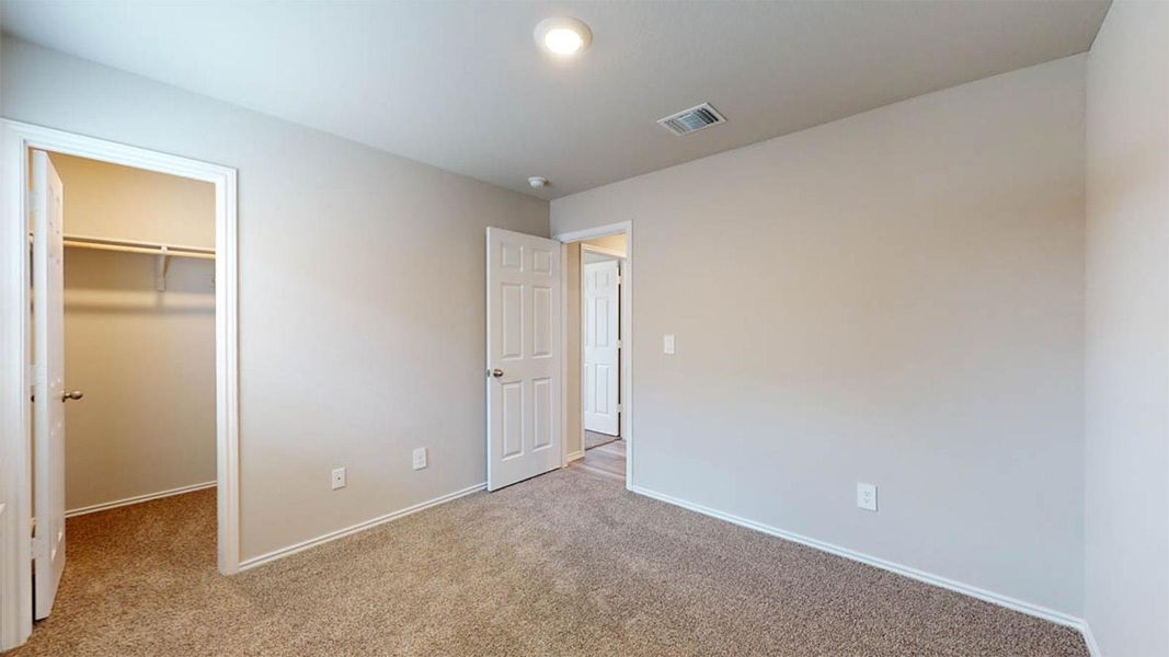 Unfurnished bedroom with a spacious closet and light colored carpet
