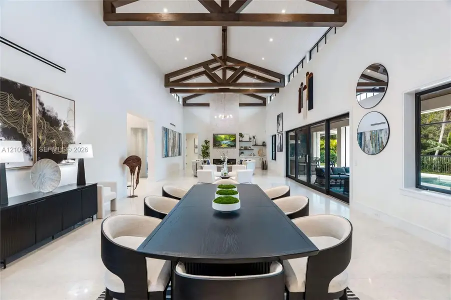 Vaulted ceilings with exposed wood beams, polished stone flooring, custom built-in cabinetry, floor-to-ceiling sliding glass doors, and a decorative tile fireplace surround Vaulted ceilings with exposed wood beams, polished stone flooring, custom built-in cabinetry, floor-to-ceiling sliding glass doors, and a decorative tile fireplace surround