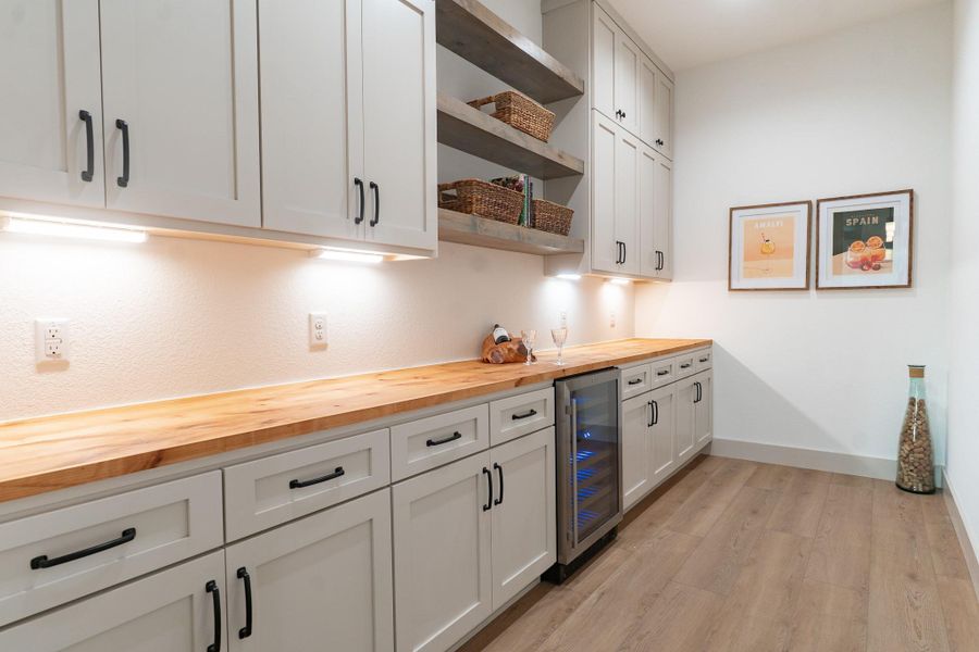 Kitchen with wood counters, open shelves, light wood finished floors, and beverage cooler Kitchen with wood counters, open shelves, light wood finished floors, and beverage cooler