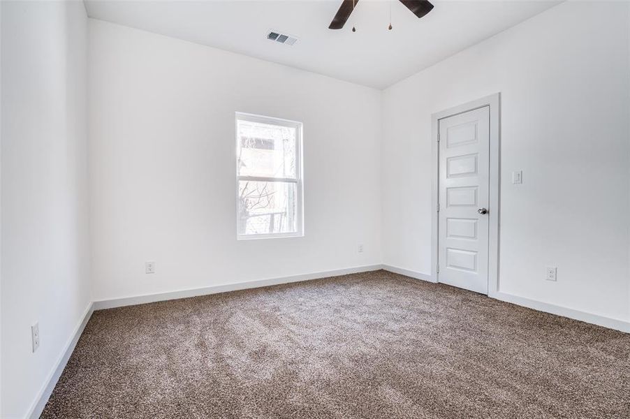 Spare room featuring carpet flooring, a ceiling fan, visible vents, and baseboards