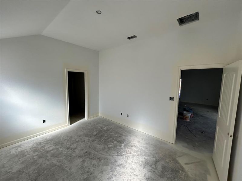 Unfurnished bedroom with concrete flooring and lofted ceiling