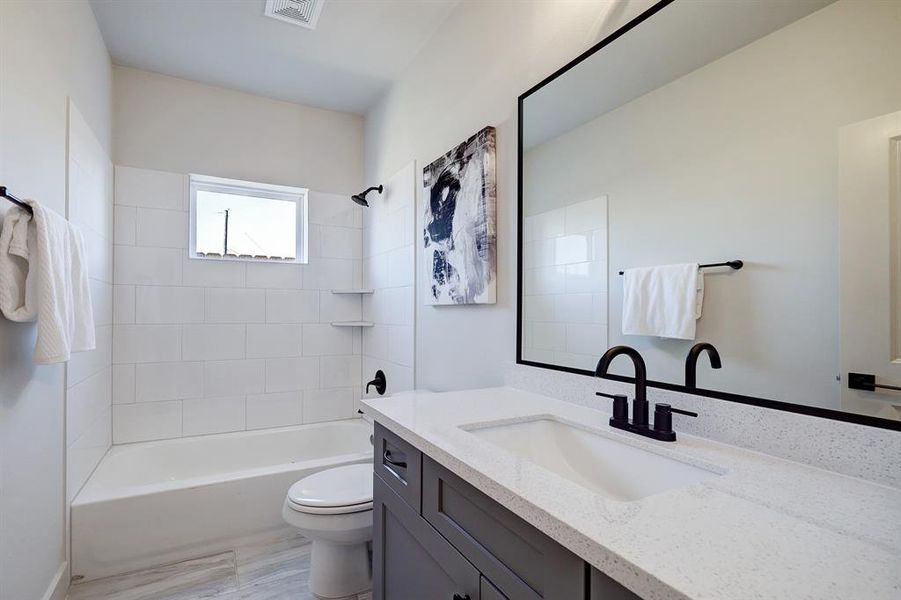 The secondary bathroom features ashower/tub combo and quartzcountertop with undermount sink aswell as framed mirror.