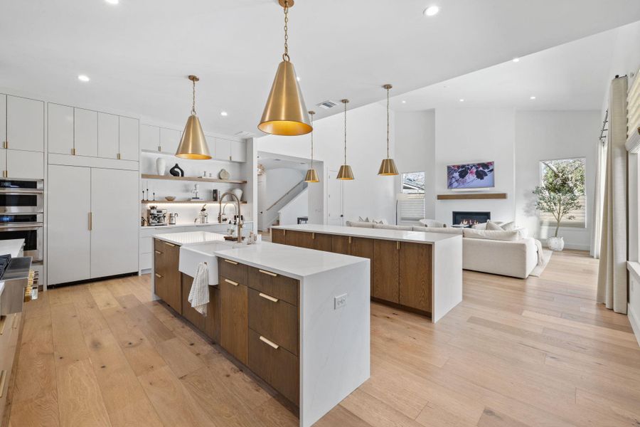 Kitchen featuring dual tone cabinets, modern cabinets, open floor plan, pendant lighting, and light wood-style floors