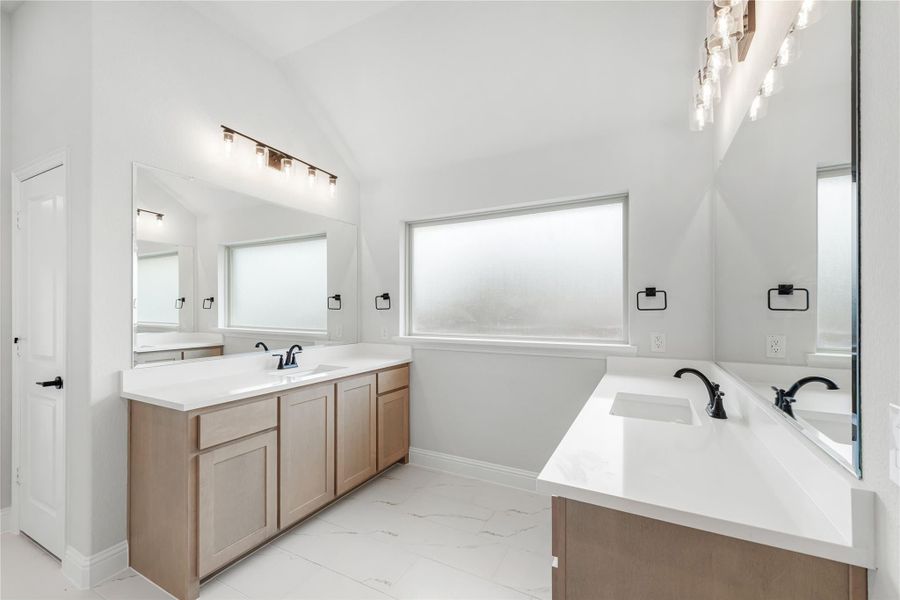 Dual-vanity master bathroom with white quartz countertops, light wood cabinets, and vaulted ceiling Dual-vanity master bathroom with white quartz countertops, light wood cabinets, and vaulted ceiling