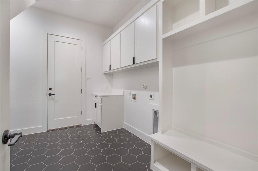 Clothes washing area with cabinets, hookup for an electric dryer, dark tile patterned floors, and hookup for a washing machine