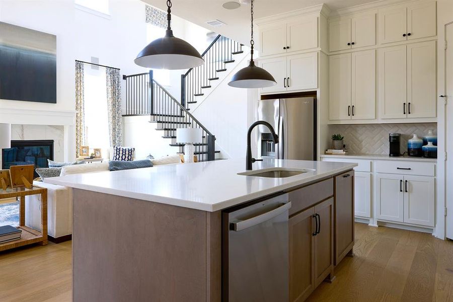 Kitchen featuring a kitchen island with sink, backsplash, a high end fireplace, open floor plan, and appliances with stainless steel finishes
