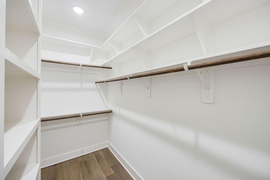 Large walk-in primary bedroom closet with built-in shelving