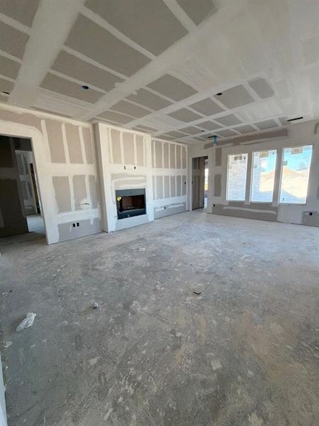 Unfurnished living room featuring a fireplace, unfinished concrete flooring, and ceiling fan