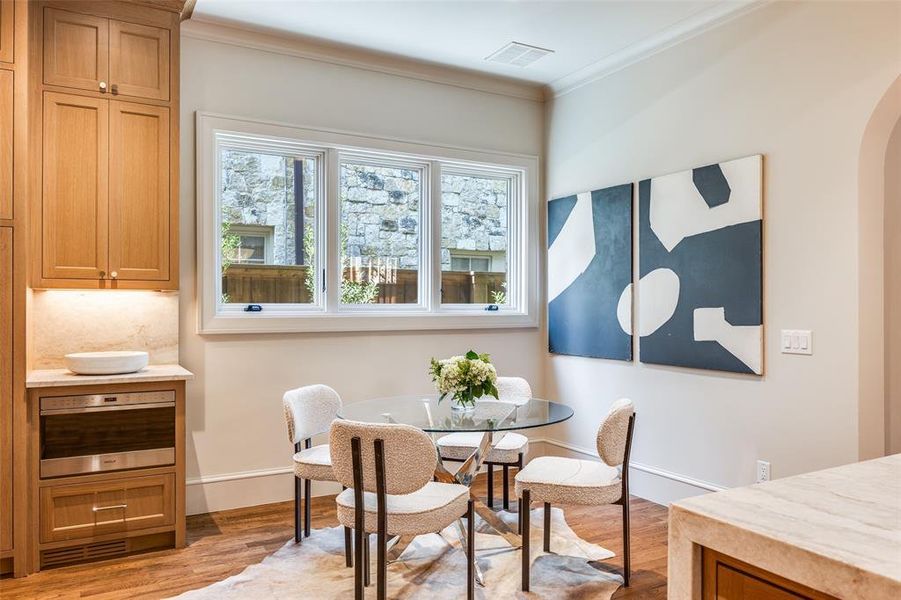 Dining room featuring crown molding, light wood-style floors, and arched walkways Dining room featuring crown molding, light wood-style floors, and arched walkways