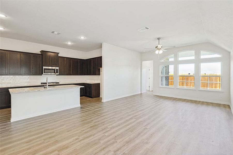 Kitchen featuring lofted ceiling, sink, tasteful backsplash, dark brown cabinets, and light hardwood / wood-style floors