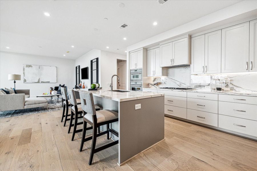 A large island with offers ample prep space and casual pull-out seating. Photos are of a similar unit with the same floor plan