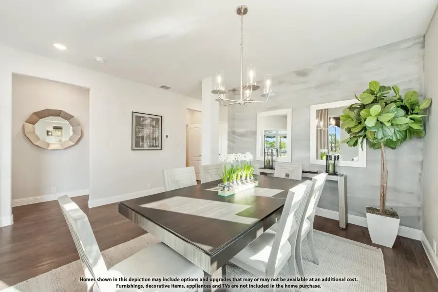 Dining room with dark wood table, white chairs, chandelier, and accent wall with hardwood floors