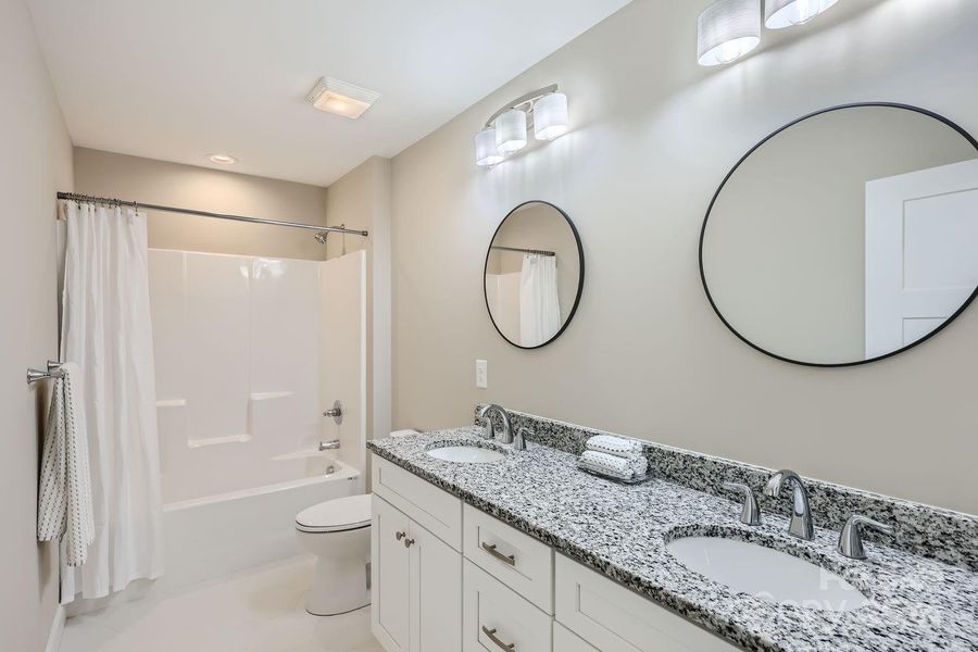 This spacious full bathroom boasts a double vanity, a soaking tub, and ample space providing both functionality and a touch of luxury.