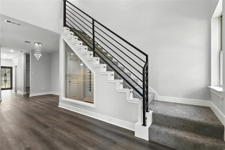 Stairs with wood finished floors and hanging lights