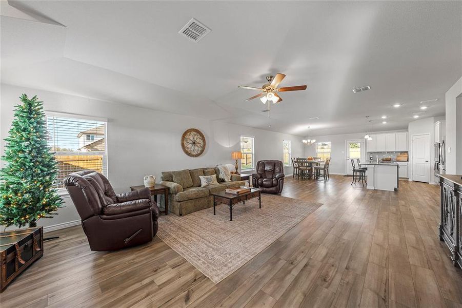 Living area with ceiling fan, dark wood-style floors, and a chandelier