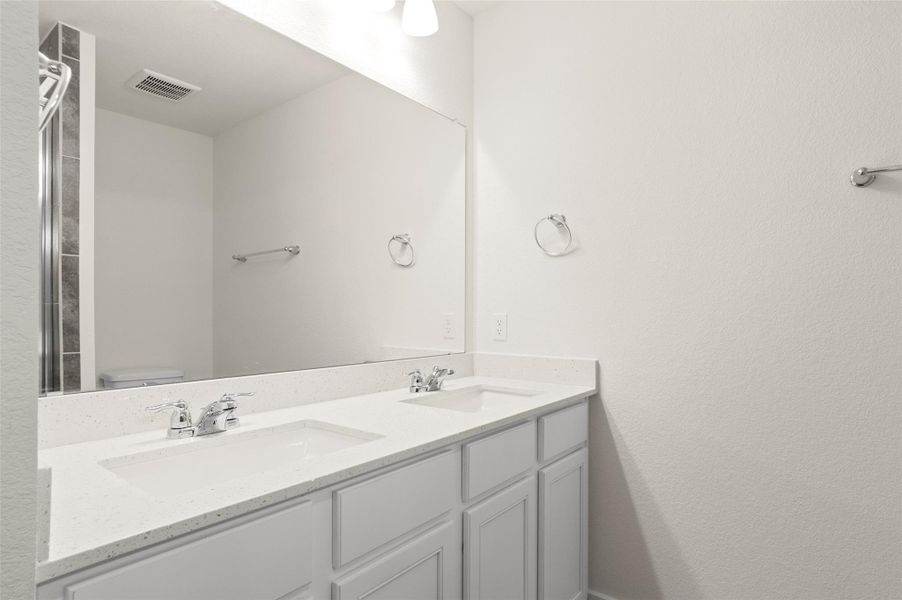 Full bath with double vanity, toilet, visible vents, and a sink