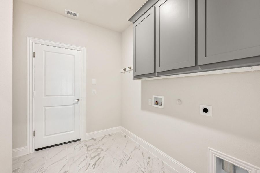 Laundry room with gray upper cabinets, washer and dryer hookups, and marble-look tile floors Laundry room with gray upper cabinets, washer and dryer hookups, and marble-look tile floors