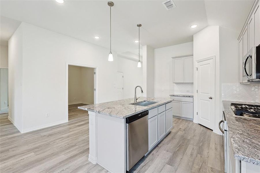 Kitchen with sink, light hardwood / wood-style flooring, decorative backsplash, and stainless steel appliances