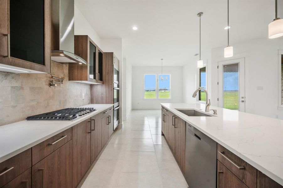Kitchen featuring modern cabinets, wall chimney range hood, a sink, backsplash, and stainless steel appliances Kitchen featuring modern cabinets, wall chimney range hood, a sink, backsplash, and stainless steel appliances